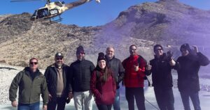 A group of guests pose after completing a tactical helicopter shooting adventure with Gunship Helicopters in the Mojave Desert near Las Vegas.