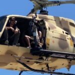 Thrill-seekers inside a tactical helicopter preparing for an aerial shooting experience with fully automatic machine guns near Las Vegas.