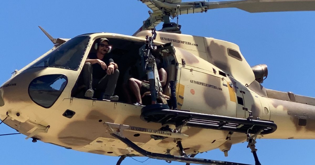 Thrill-seekers inside a tactical helicopter preparing for an aerial shooting experience with fully automatic machine guns near Las Vegas.