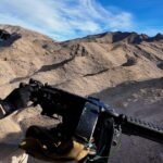 Man firing fully automatic machine gun from helicopter over Mojave Desert during aerial shooting tour in Las Vegas