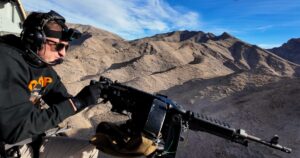 Man firing fully automatic machine gun from helicopter over Mojave Desert during aerial shooting tour in Las Vegas