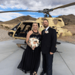 Bride and groom pose in front of a tactical helicopter at Gunship Helicopters’ desert landing zone after their unique Las Vegas helicopter wedding experience.