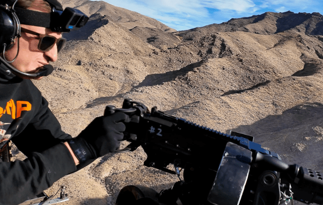 Person shooting an M249 from a helicopter door gunner seat over Las Vegas desert