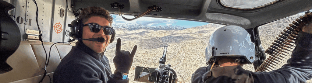 privacy / tour policy - Cookie Policy - news : Guest giving hand sign inside helicopter mid-flight with gun mounted