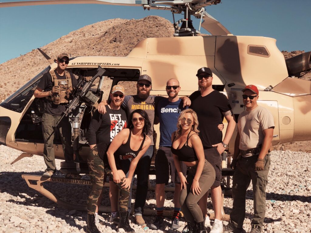 Group posing in front of helicopter after completing the Deluxe Beast Mode shooting experience at Gunship Helicopters