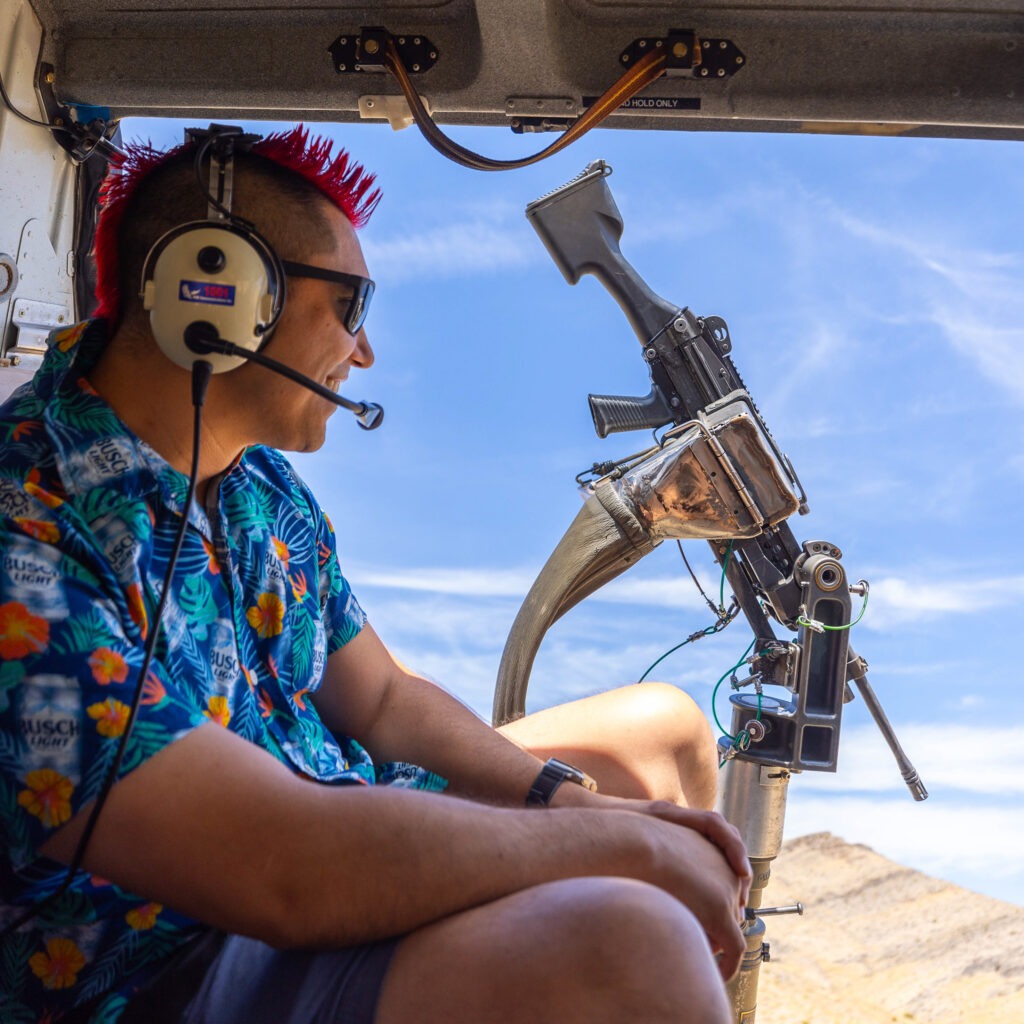 Man smiling inside helicopter with mounted machine gun during Gunship Helicopters Ultimate Fully Loaded package in Las Vegas
