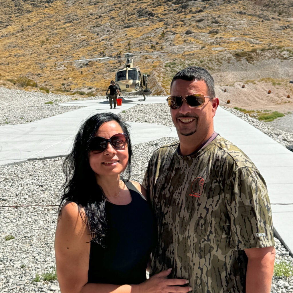 2 people: Couple smiling after shooting experience with gunship helicopter