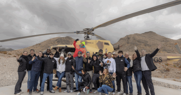 Corporate group adventure at Gunship Helicopters in Las Vegas, posing safely in front of the helicopter before aerial shooting experience.