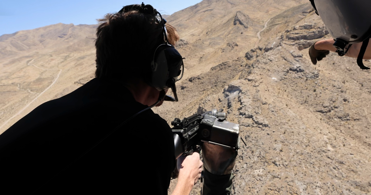 Guest guided by range safety officer during helicopter shooting experience over the Mojave Desert near Las Vega