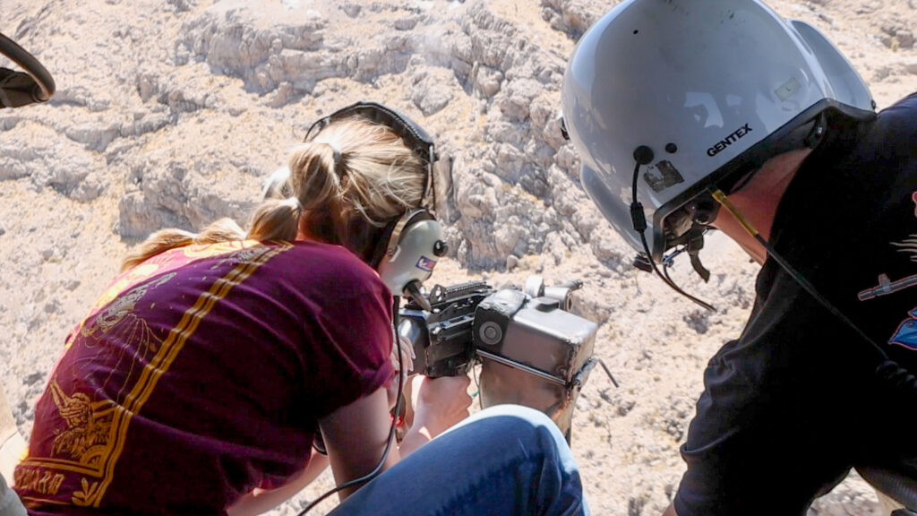 Range safety officer guiding a guest during an aerial shooting safety procedure inside a Gunship Helicopters aircraft over the Nevada desert