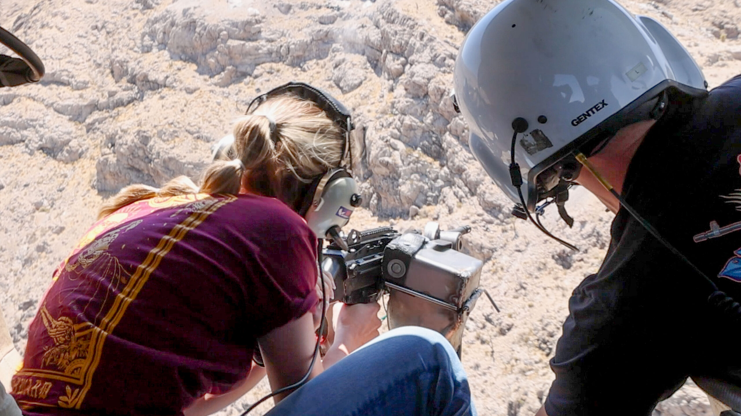 Range safety officer guiding a guest during an aerial shooting safety procedure inside a Gunship Helicopters aircraft over the Nevada desert