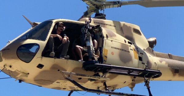 Guests participating in a helicopter shooting experience over the Mojave Desert during a high-adrenaline Las Vegas adventure experience.