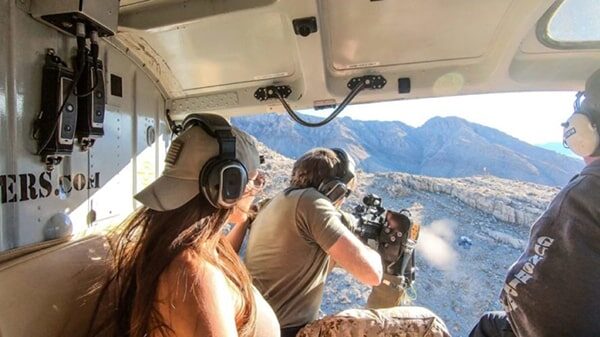 Guest taking part in a helicopter shooting experience with guidance from range safety officers during an aerial adventure near Las Vegas