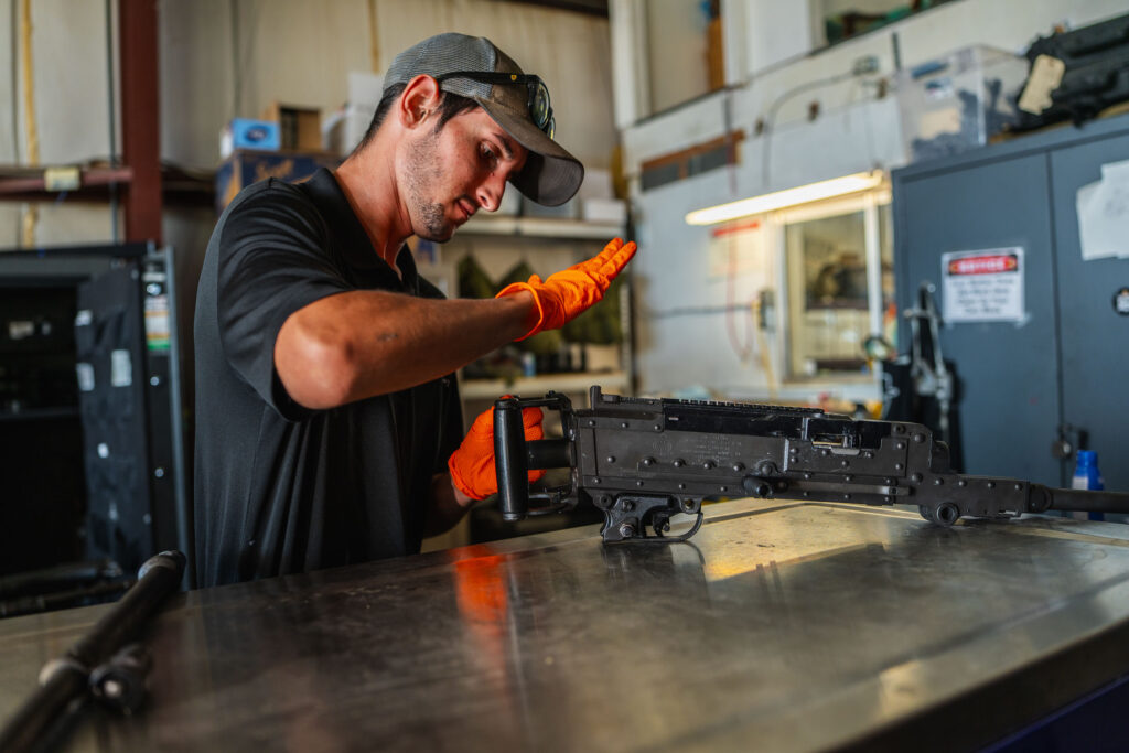 Gunship Helicopters team member inspecting an M240 for helicopter gun range Nevada safety and aerial shooting preparation