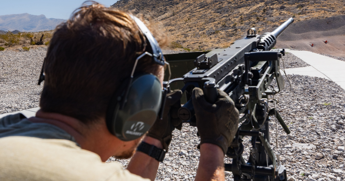 Guest participating in a ground shooting experience using an M240 mounted fully automatic machine gun at an outdoor shooting range near Las Vegas.