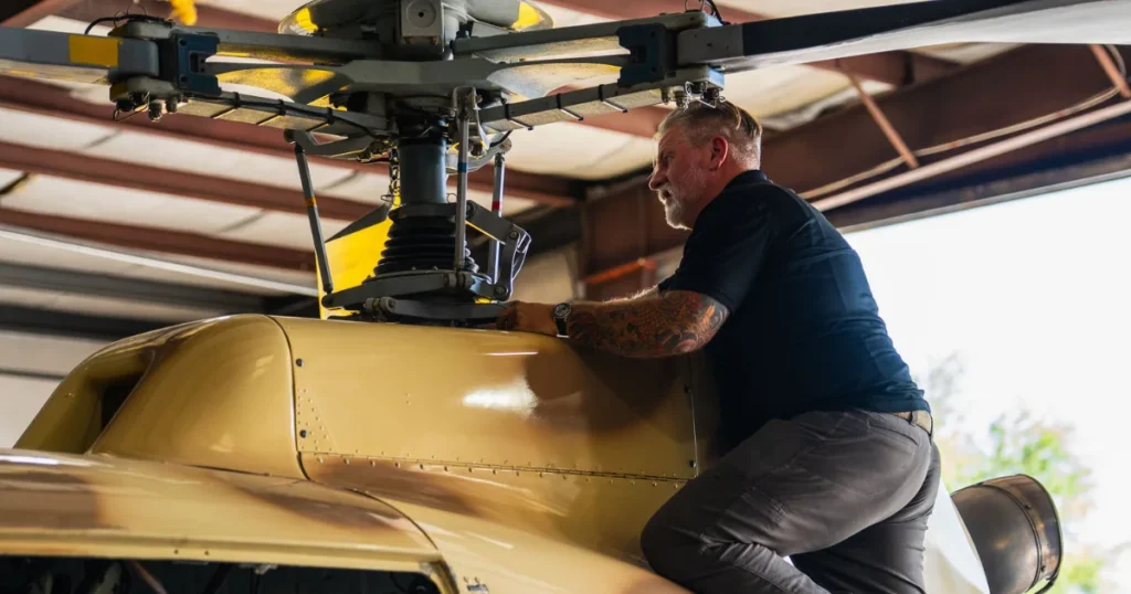 Aviation pilot and technician inspecting the rotor system of an A-Star turbine helicopter inside a hangar